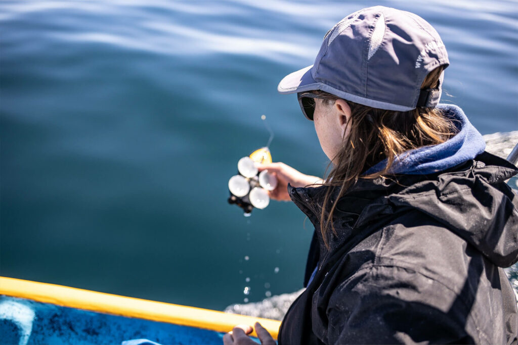 Woman looks at equipment in a boat on the water.